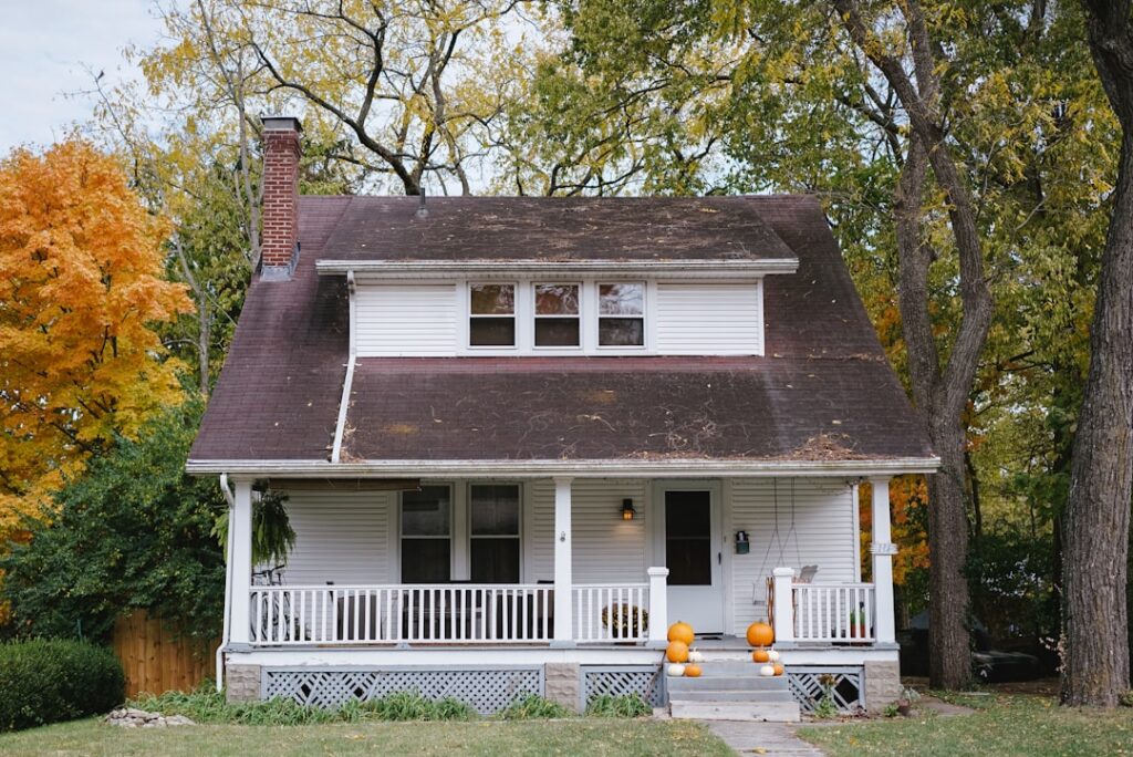 White cape cod style family home with a front porch and autumn trees