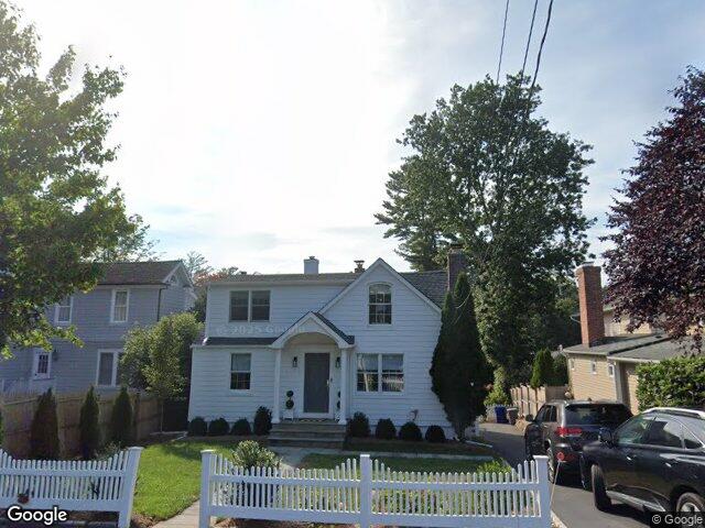 A white colonial with dormers and a picket fence on Highland Avenue in Norwalk